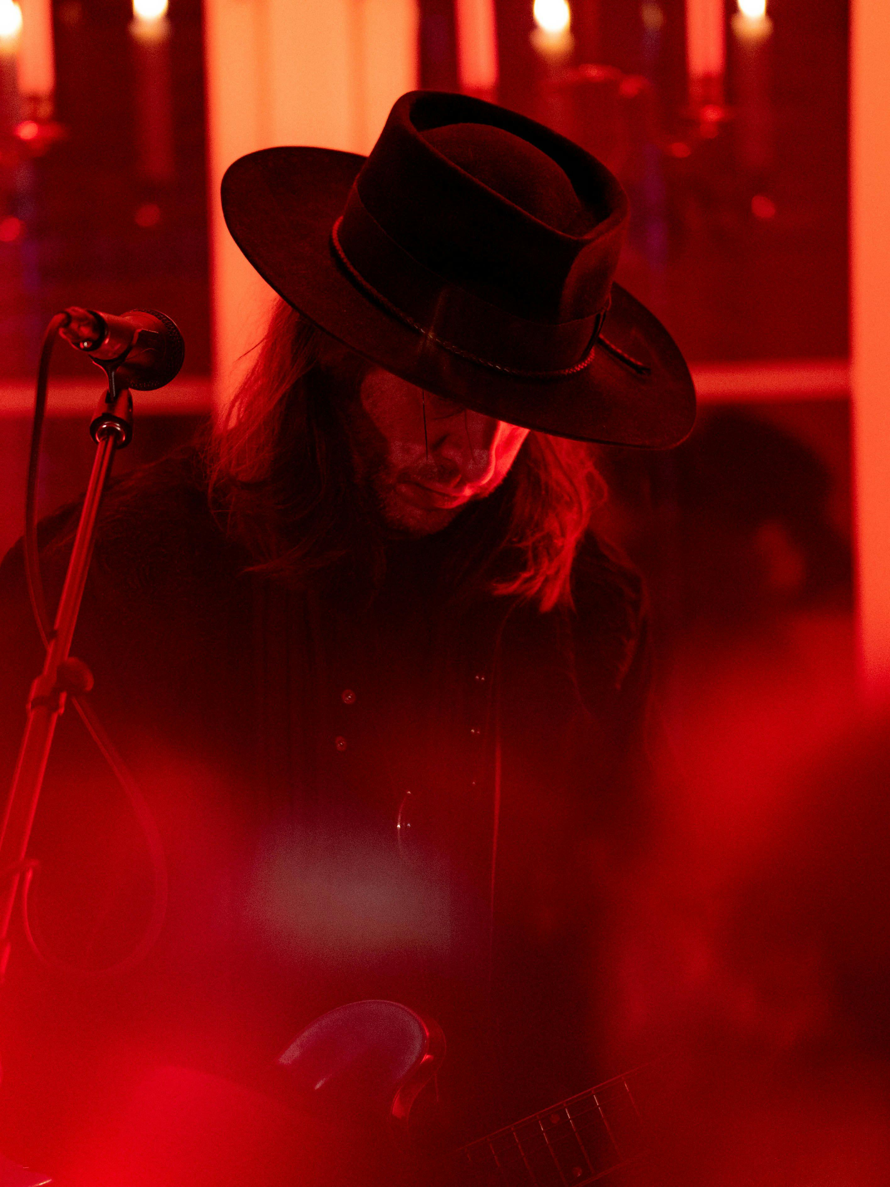 Mannlig artist med svart hatt, som ser ned på gitaren
