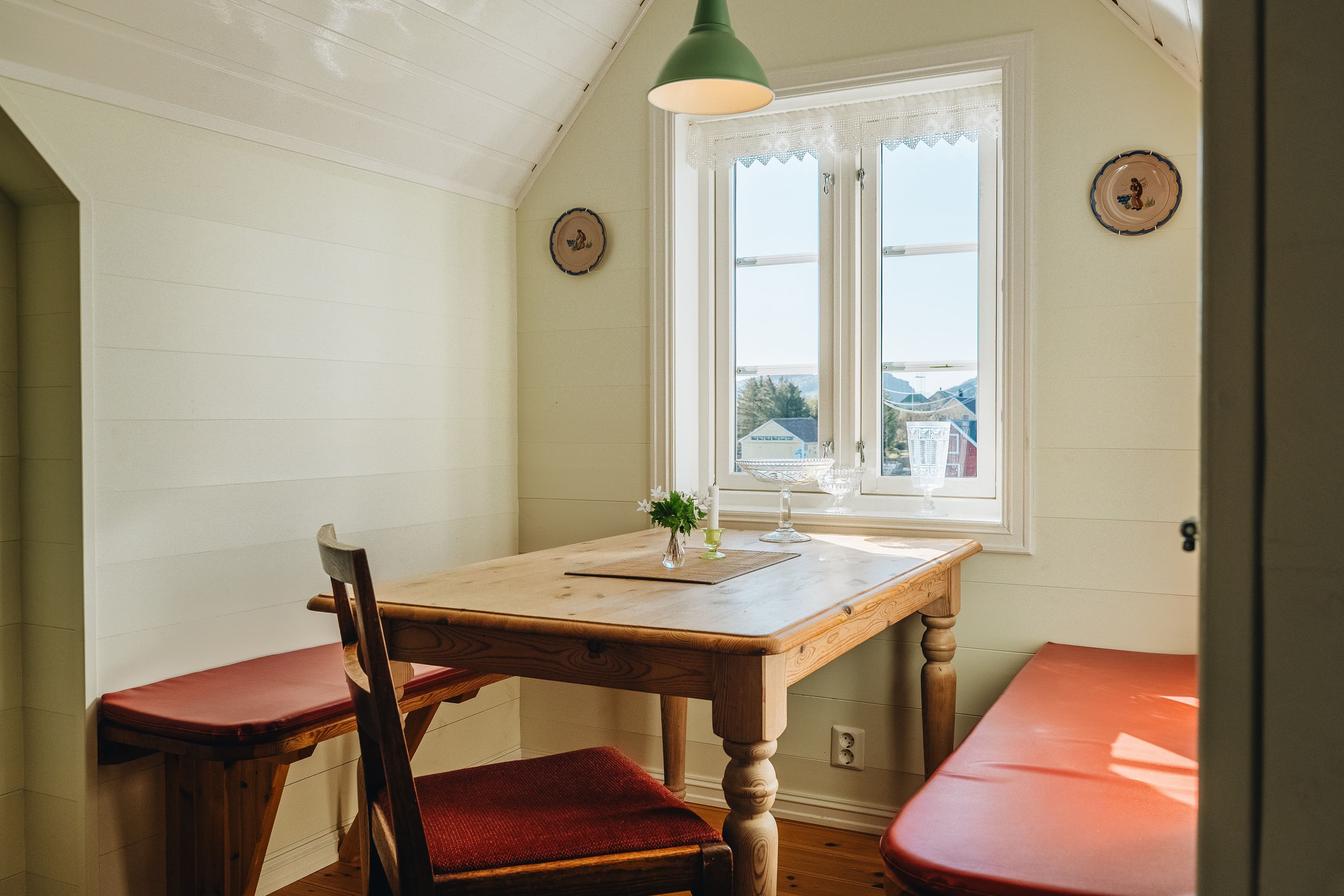 Spisekrok med to benker og et lite bord under et vindu
