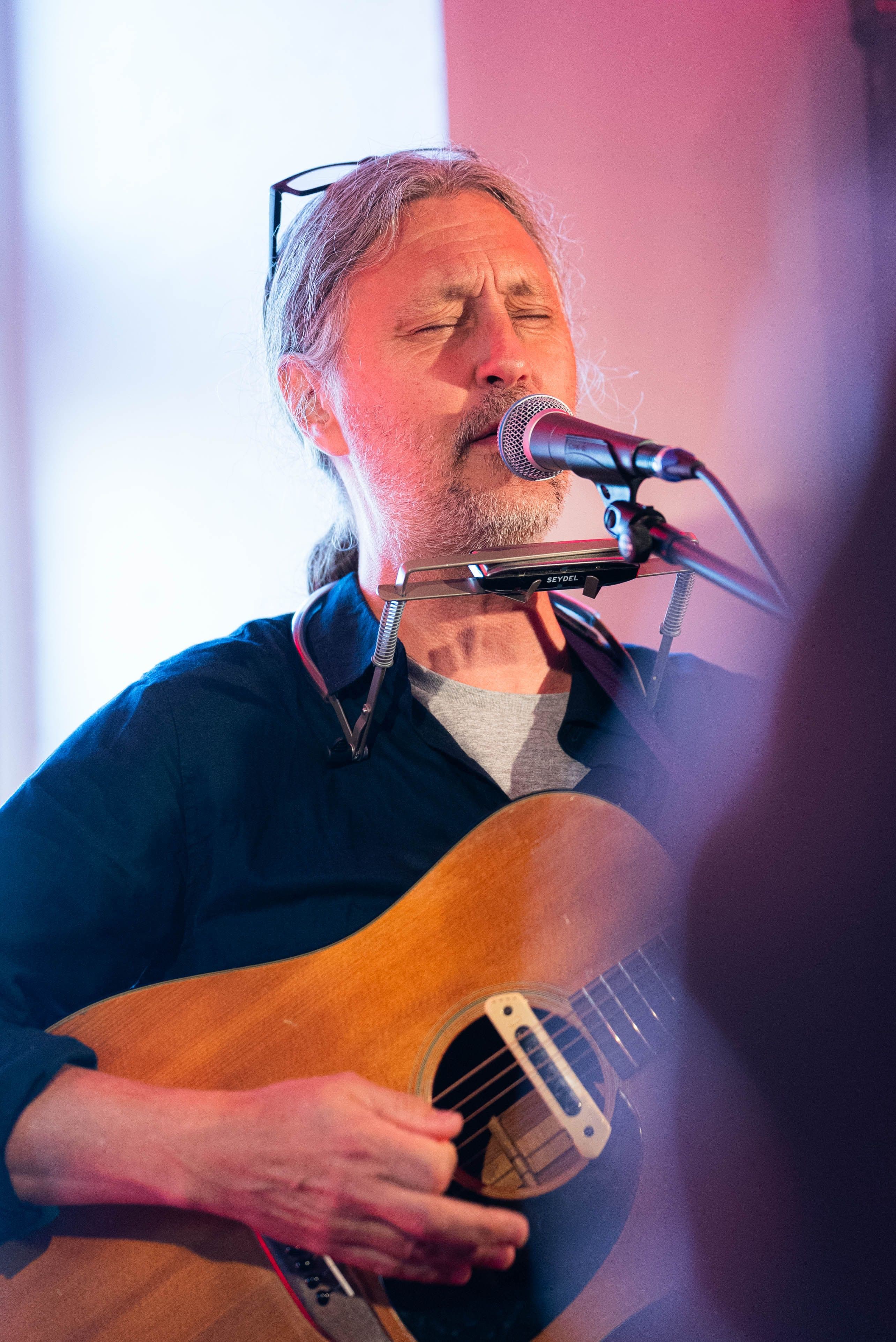 Mannlig vokalist synger og spiller gitar med lukkede øyne.