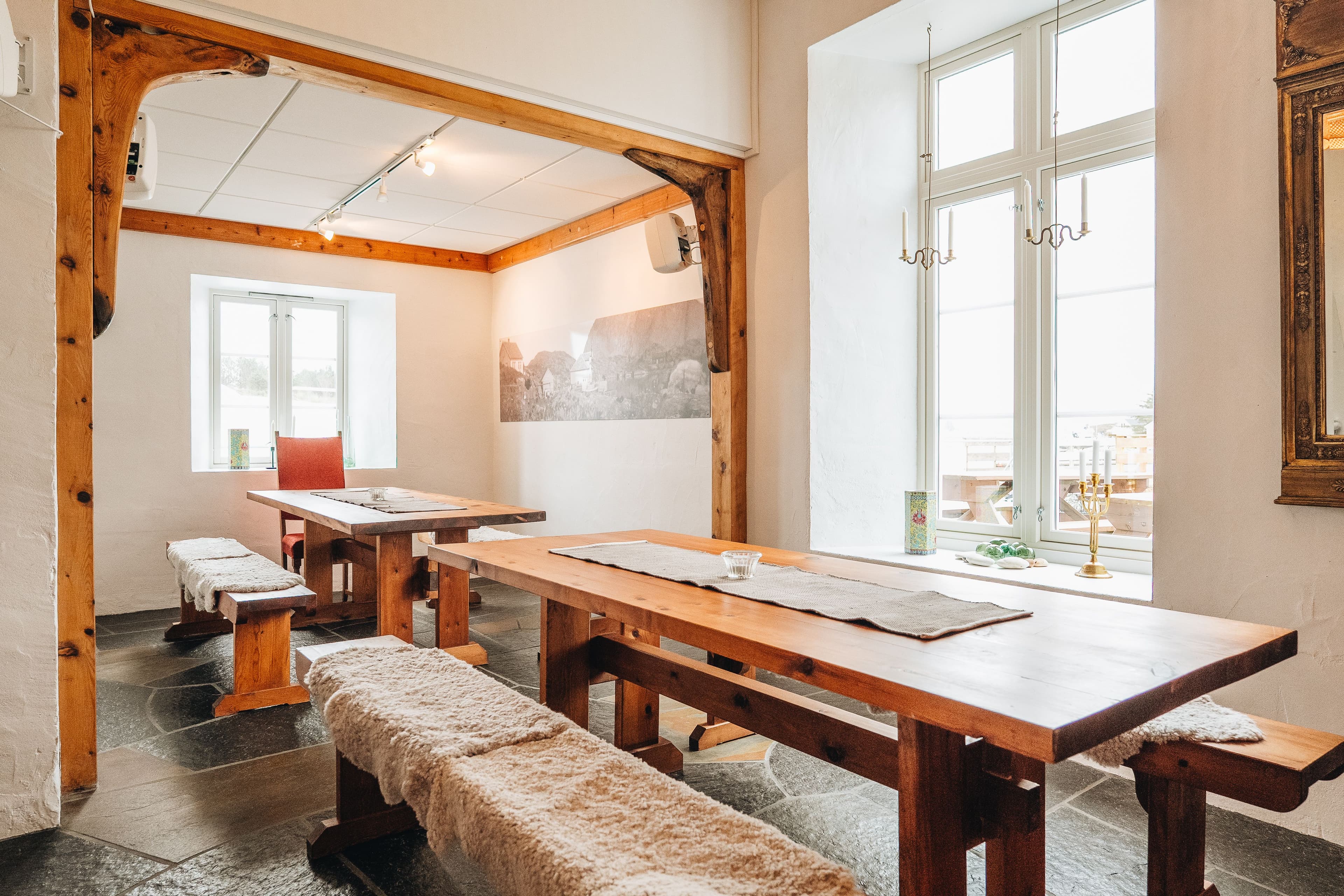 Varmt selskapslokale med peis i forgrunnen, og piano i bakgrunnen