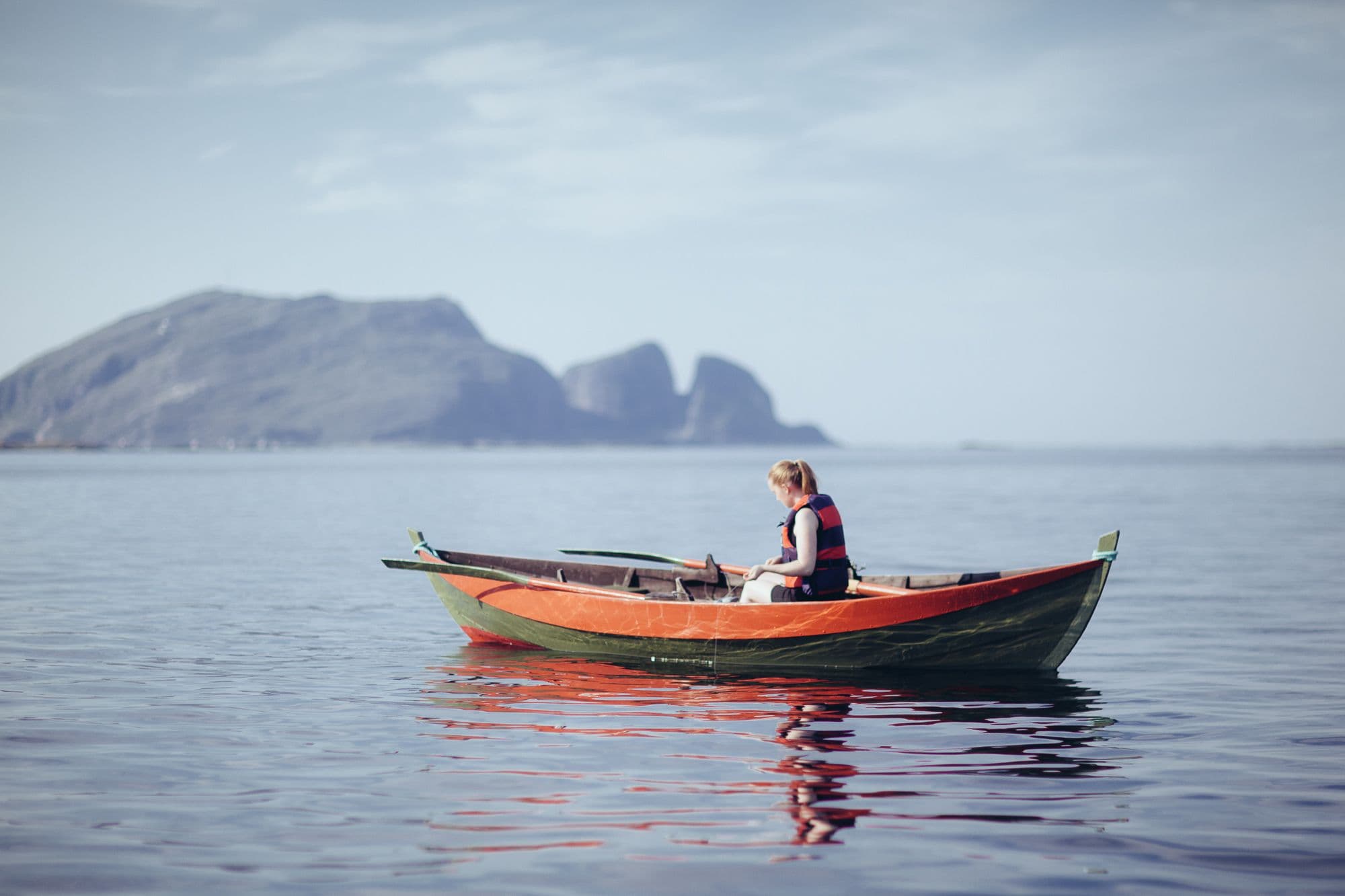 Kvinne i robåt med Kinnaklova i bakgrunnen
