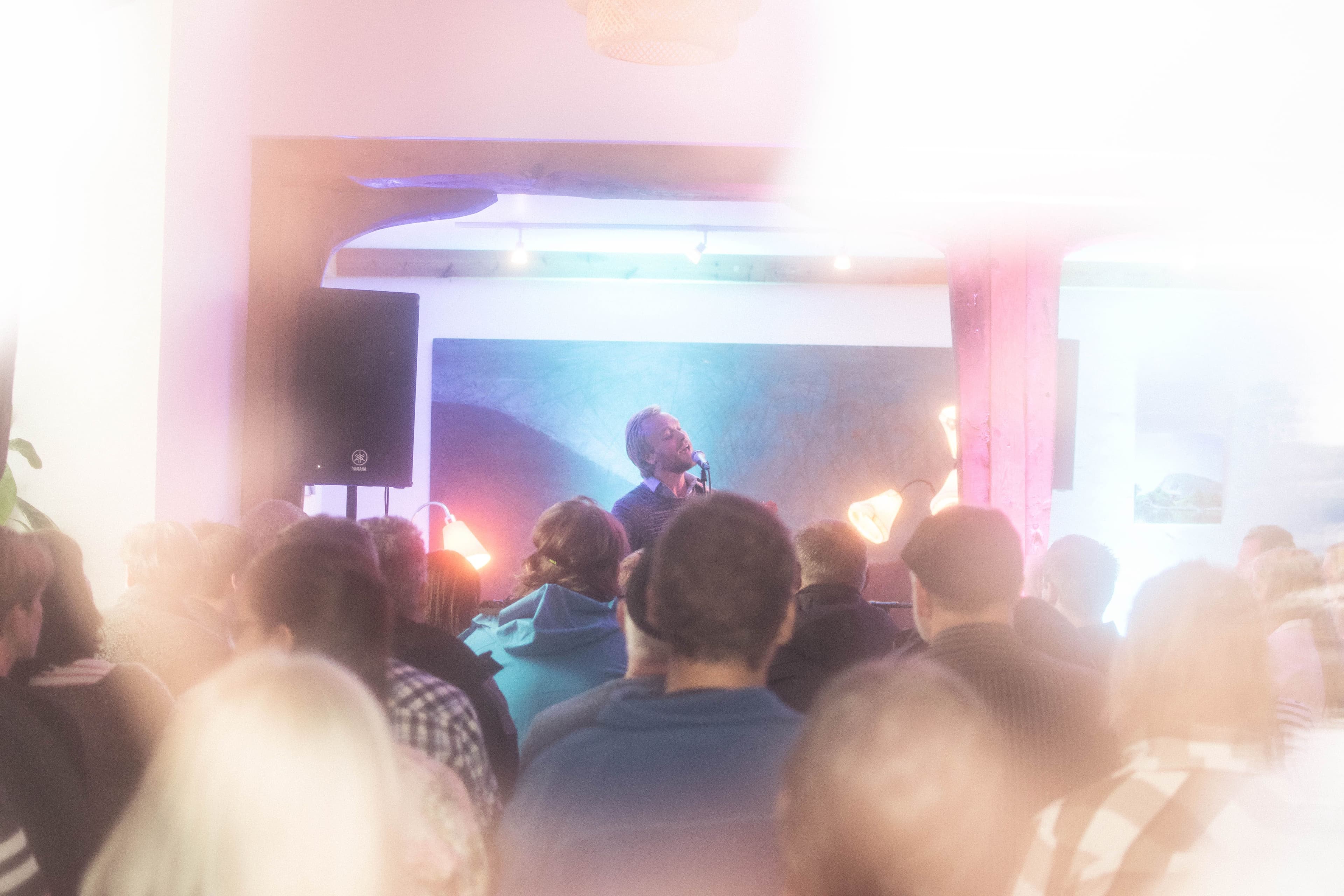 En mannlig vokalist som synger, med flere publikummere i forgrunnen