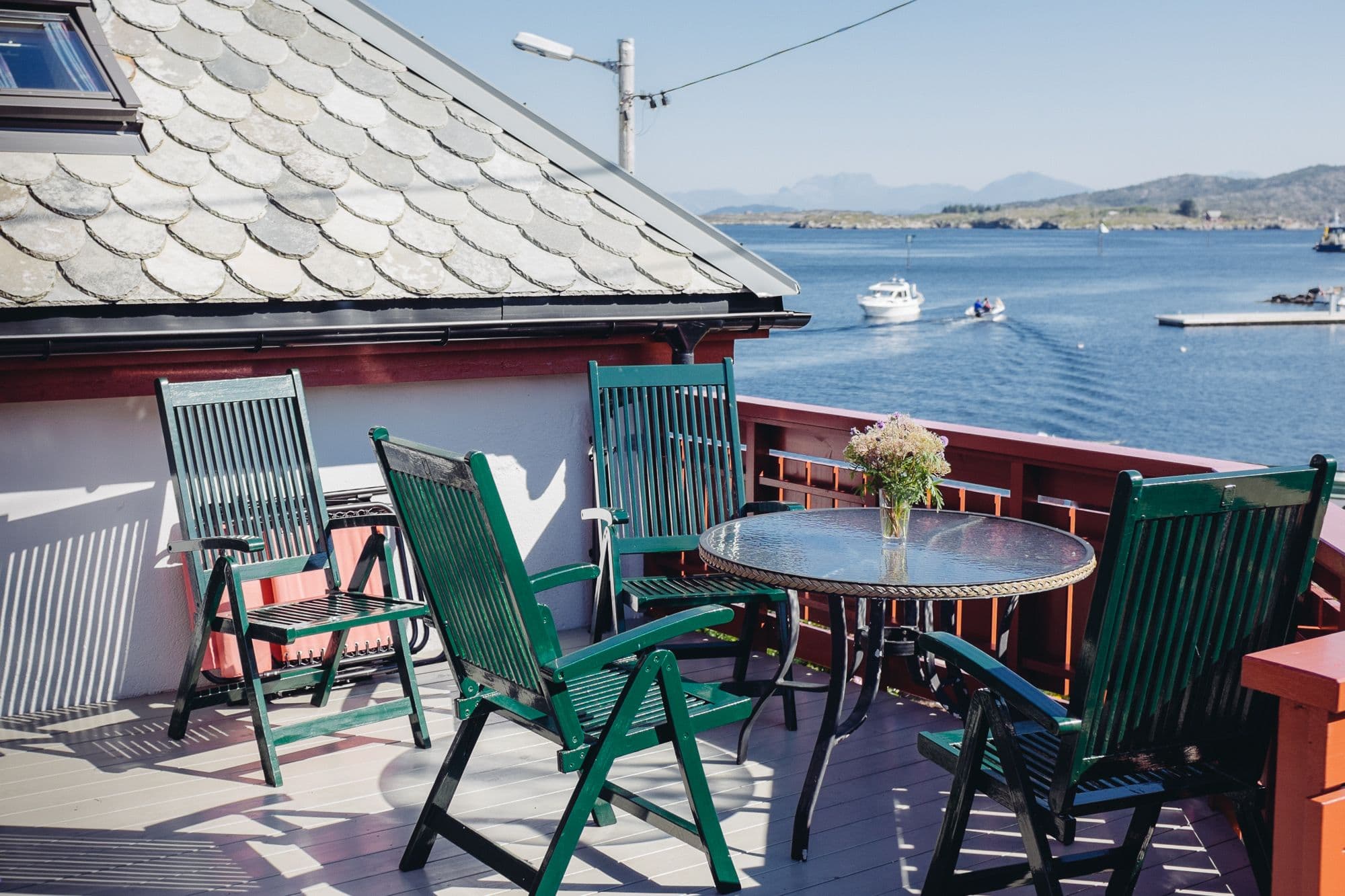 Terrasse med bord og stoler, og båter i bakgrunnen